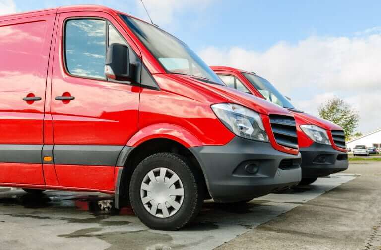 Two red vans parked in parking