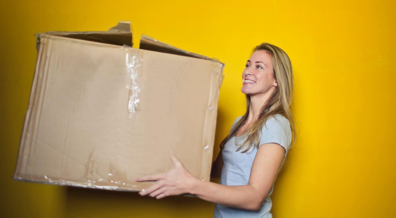 Blonde lady carries a moving cardboard box 