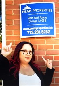 lady standing and pointing at peak properties sign